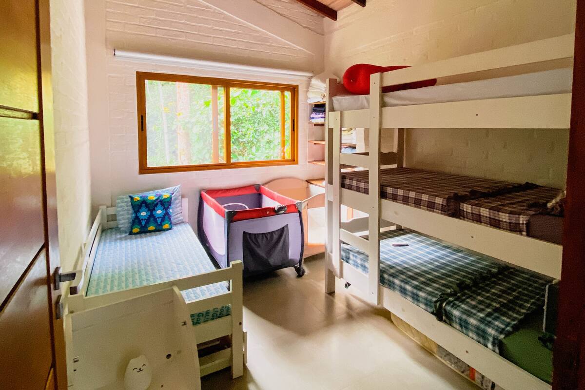Quarto compacto com beliches, escrivaninha e janela.
