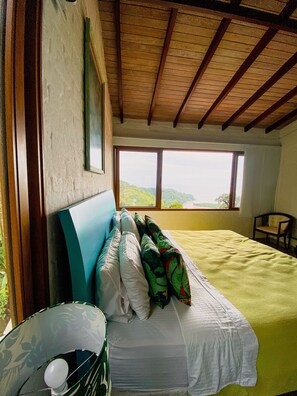 A bedroom with a bed, a chair, a window, and a view of the outdoors. - Paraiso em Juquehy (São Sebastião)