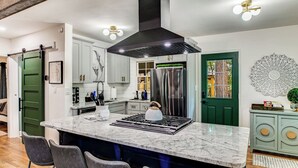Una cocina moderna con una isla grande, electrodomésticos de acero inoxidable y una lámpara de techo original.