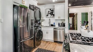 Une cuisine moderne équipée d’appareils électroménagers en acier inoxydable, d’un lave-linge et d’une cuisinière à gaz.