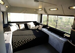 Relax in a serene room with a large bed, patterned bedspread, and a window offering a view of the surrounding green landscape.