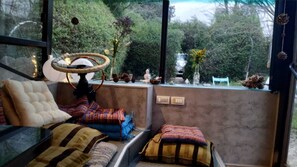 Relax in a cozy space with plush seating, a unique light fixture, and a view of lush greenery.