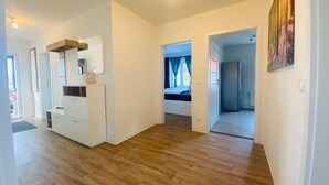 Ein geräumiges Zimmer mit Holzboden, einem Einbauschrank, einem Bett mit Fenster und einer Tür zu einem anderen Raum.