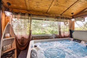 A wooden cabin interior with a hot tub, wooden shelves, and a window with curtains. - Swan River House With Sauna & Jacuzzi (Lasinja)