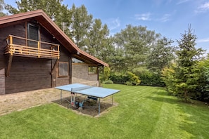 A wooden cabin with a balcony, a ping pong table in the yard, and a well-maintained lawn. - Swan River House With Sauna & Jacuzzi (Lasinja)