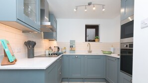 Una cocina moderna con armarios grises, encimera blanca y horno integrado.