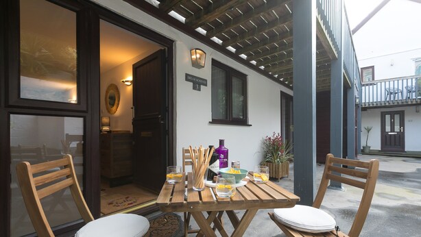 Un área de comedor al aire libre con mesas y sillas de madera, un letrero que dice 