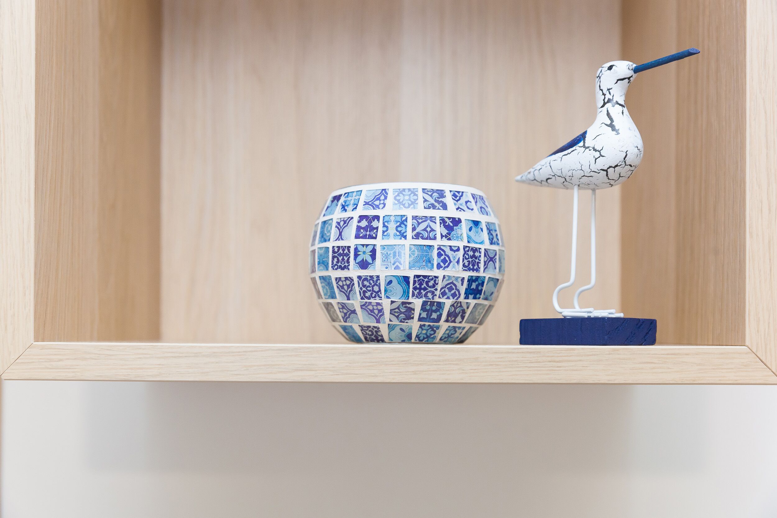 A shelf with a decorative bird and a patterned bowl.