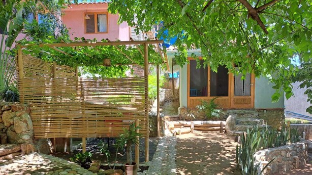 Un jardín con una celosía de bambú, un sendero de piedra y plantas en macetas.