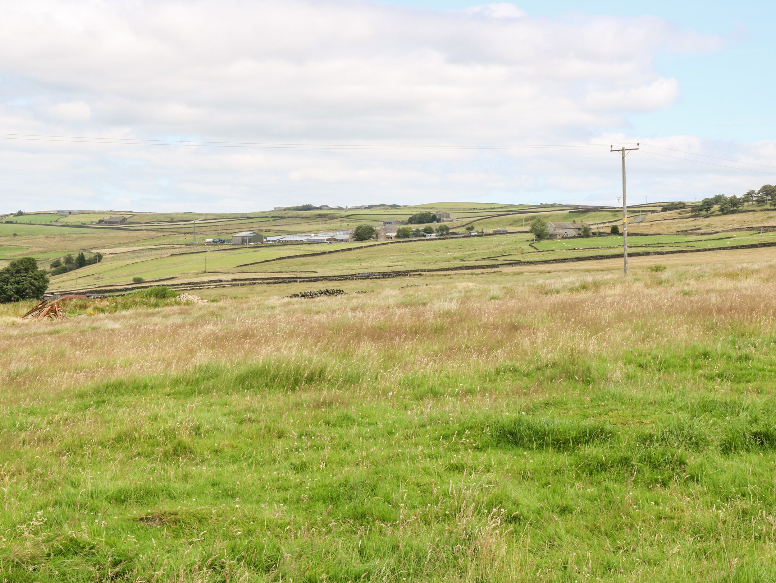 A rural landscape with rolling hills, a few scattered buildings, and a utility pole.