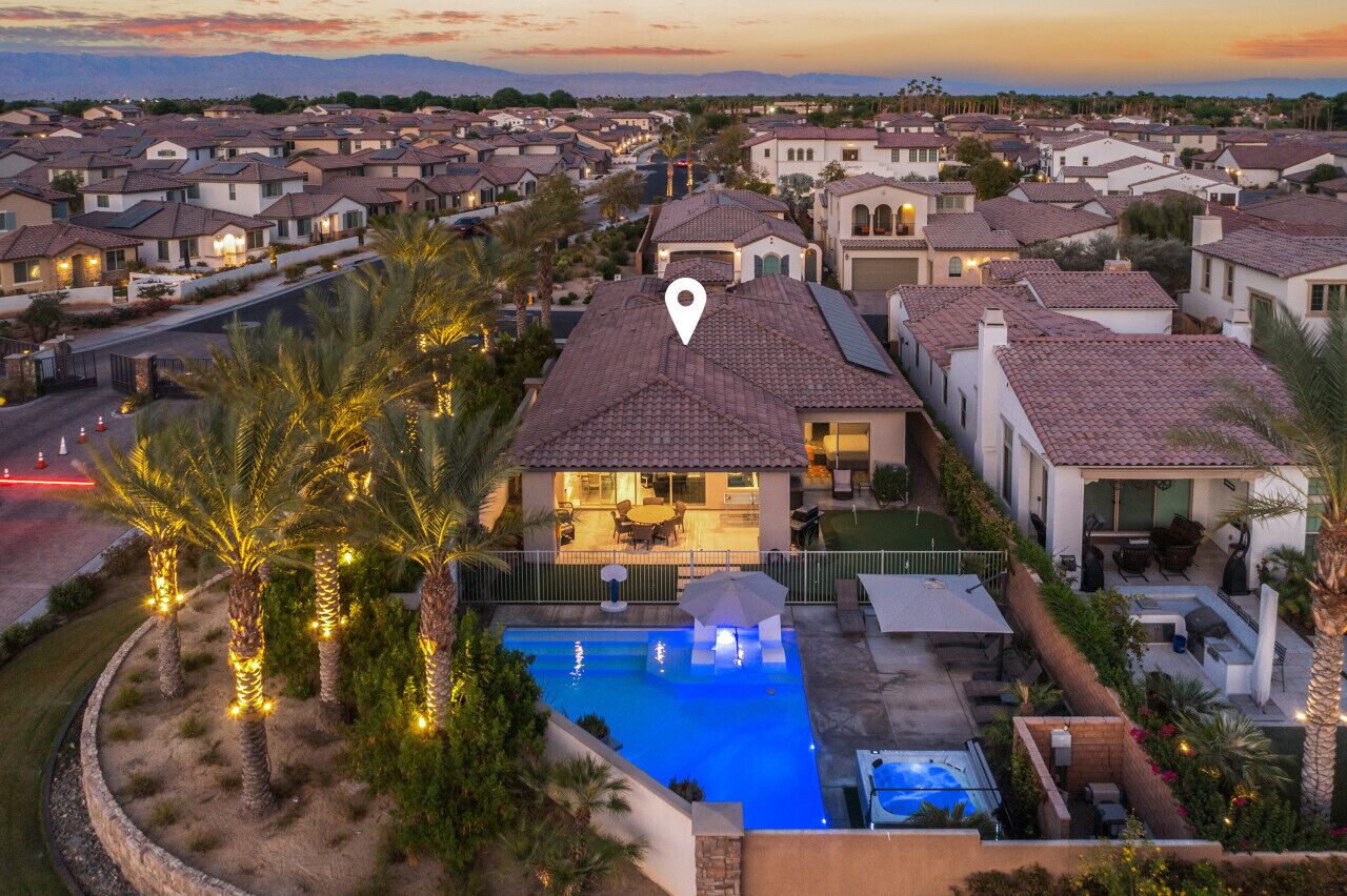 A residential area with houses, a swimming pool, and palm trees.