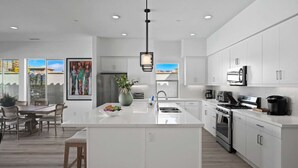 Une cuisine moderne avec des meubles blancs, un îlot central et un coin repas comprenant une table et des chaises.