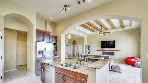 A spacious kitchen with a central island, built-in appliances, and an open layout leading to a living area with a TV and seating. - Unique Las Cruces Home w/ Patio + Gas Grill! (Las Cruces)
