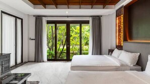 A modern bedroom with a large bed, a desk, and a view of greenery through the sliding doors. - Sclass Pool Villa, City area and airport (.)