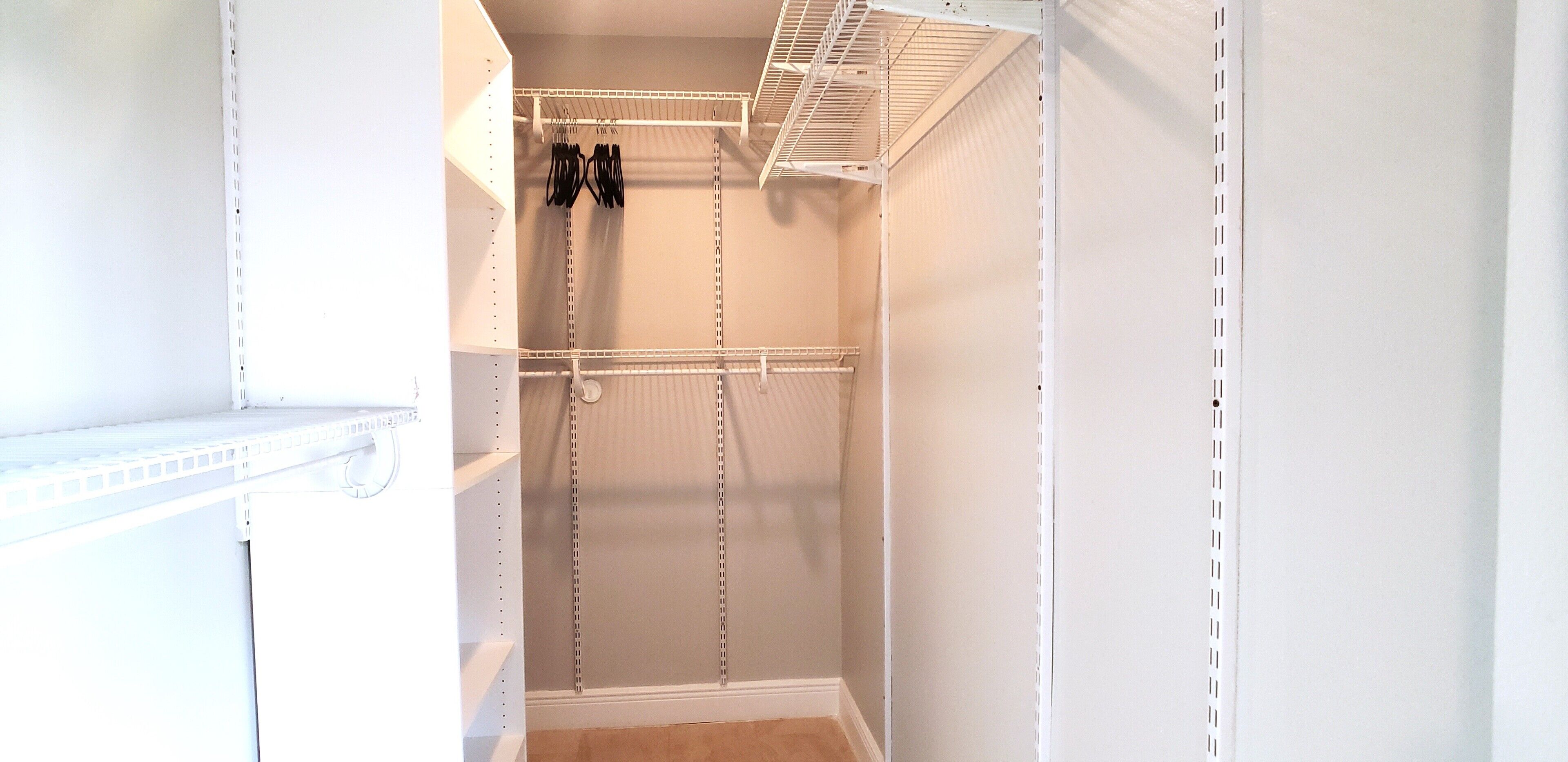 A walk-in closet with white shelving and hanging space.