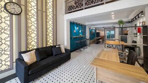 Un interior moderno con un sofá negro, una mesa de comedor de madera y una zona de cocina con taburetes de bar.