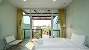 Una habitación de hotel con una cama grande, un banco y un balcón con vistas.