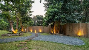 A garden with a wooden fence, a gravel path, and trees. - Zen Maekampong Waterfall Ryokan (.)