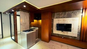 A modern kitchen with a built-in stove, a television mounted on a marble wall, and wooden cabinetry. - Calle 76 Apto 3 by Caribecheap (Barranquilla)
