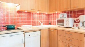 Una cocina con armarios de madera, microondas, tostadora y lavavajillas.
