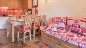 Una cocina acogedora con armarios de madera, una mesa de comedor con sillas y un sofá con cojines estampados.