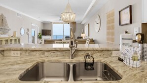 A modern kitchen with a double sink, stainless steel faucet, and a hanging light fixture.