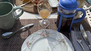 A table set with croissants, a coffee pot, a teapot, a glass of juice, and a plate of food.