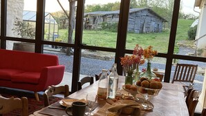 Una mesa de comedor lista para una comida, con vista a un rústico edificio de madera y un sofá rojo al fondo.