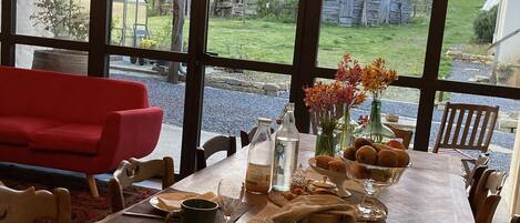 Una mesa de comedor lista para una comida, con vista a un rústico edificio de madera y un sofá rojo al fondo.