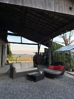An outdoor seating area with wicker furniture and a view of the countryside.