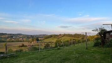 A rural landscape with rolling hills, a wooden fence, and a small house.