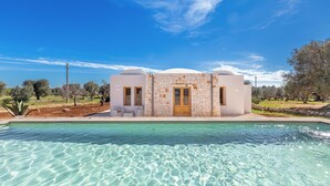 A modern house with a pool in front, surrounded by trees and clear skies. - Trullo Sorrentino Luxury by Perle di Puglia (Ostuni)