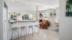 Een moderne keuken met een bar, barstoelen en een zithoek met een bank en stoelen.