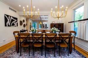 A dining area with a large wooden table, six chairs, and a chandelier. - 2027 OPEN! Union Pier Home With Pool and Hot Tub! Close To Private Beach! (Union Pier)