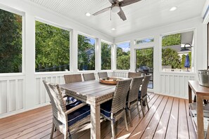 A covered patio with a wooden table and wicker chairs, surrounded by white railings and large windows. - 2027 OPEN! Union Pier Home With Pool and Hot Tub! Close To Private Beach! (Union Pier)