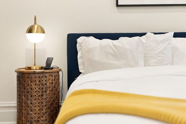 A neatly made bed with white pillows and a yellow blanket, a bedside table with a lamp, and a wall-mounted picture frame. - 2027 OPEN! Union Pier Home With Pool and Hot Tub! Close To Private Beach! (Union Pier)