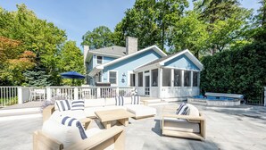 A modern outdoor living area with a pool, wooden furniture, and a covered patio. - 2027 OPEN! Union Pier Home With Pool and Hot Tub! Close To Private Beach! (Union Pier)