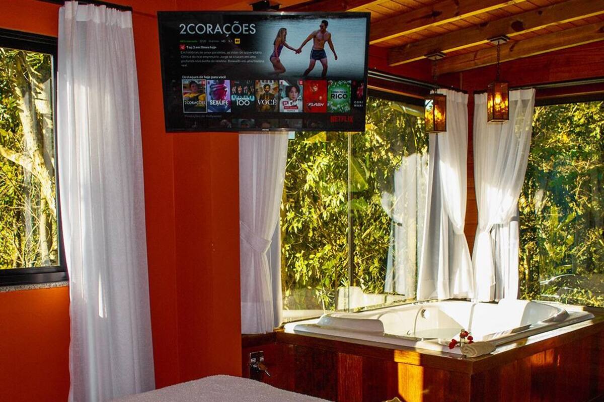 Ein Schlafzimmer mit einem großen Bett, einer Holzwanne und einem Fernseher, der ein Programm zeigt.