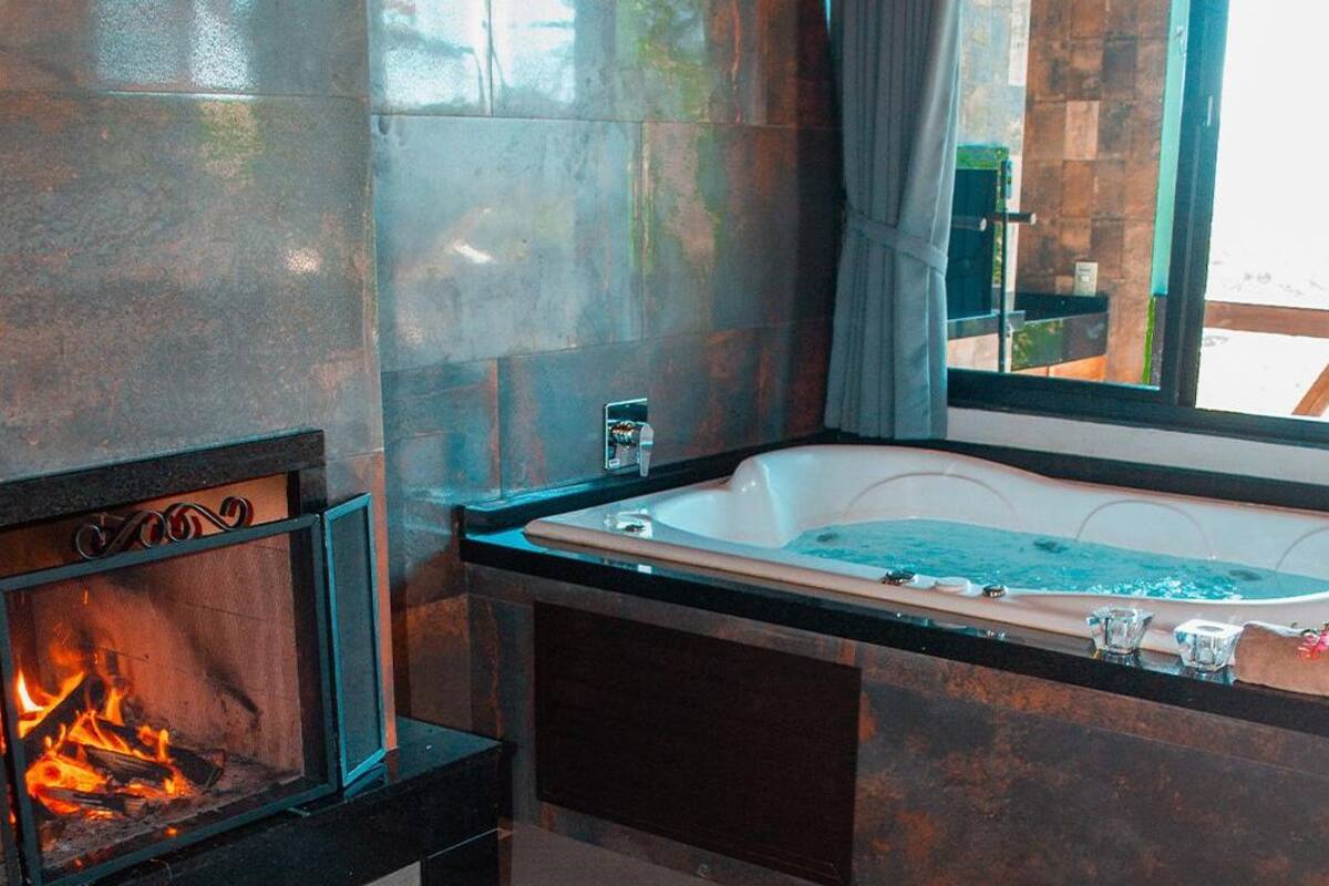 Ein modernes Badezimmer mit einer großen Badewanne, einem Kamin und Blick ins Freie.