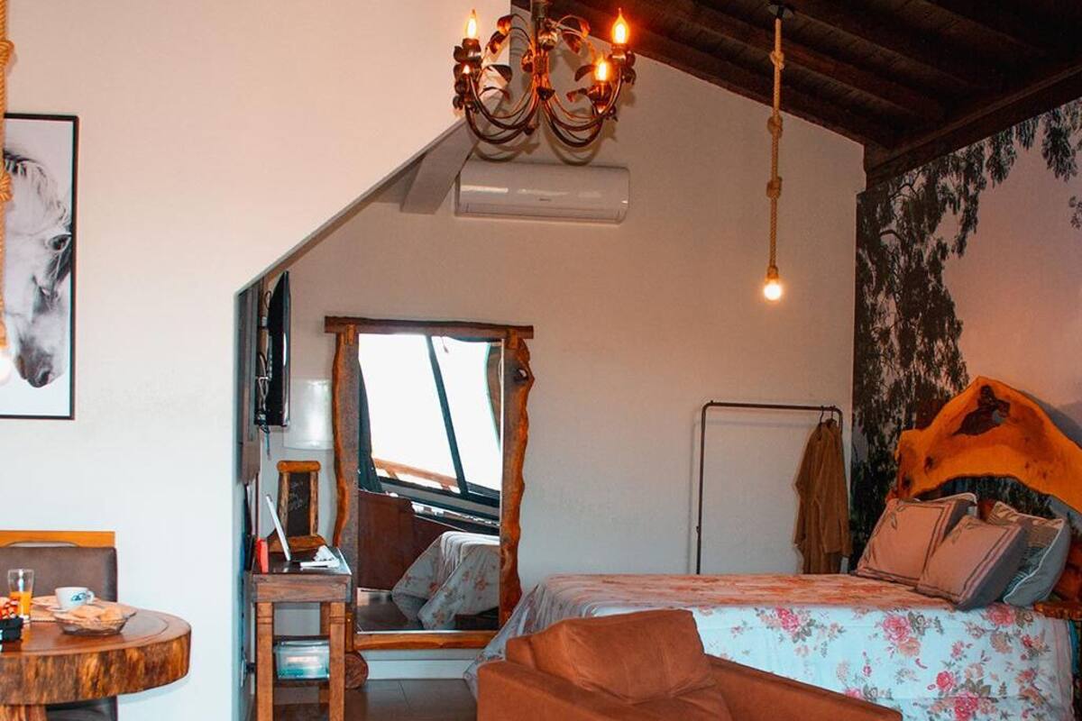 Ein Schlafzimmer mit Bett, Sessel, Tisch, Spiegel und einer Chandelier.
