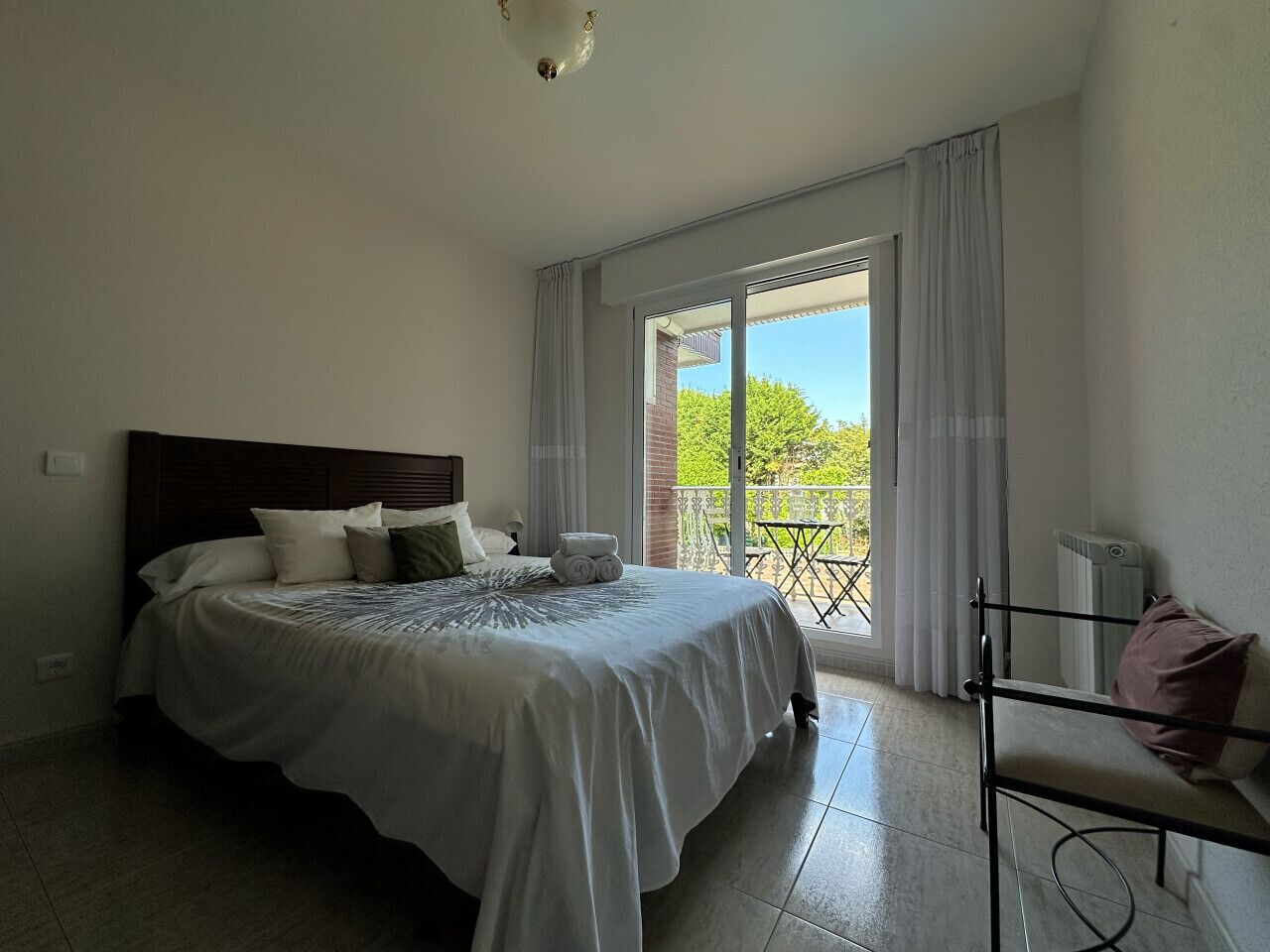 Un dormitorio con una cama grande, una silla y vistas a un balcón.