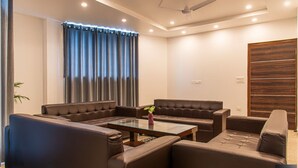 A modern living room with leather sofas, a glass coffee table, and a ceiling fan. - The Cloud Berry (Kasauli)