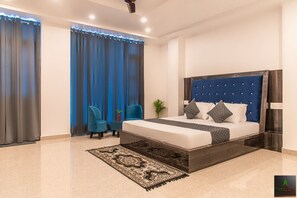 A modern bedroom with a large bed, dark headboard, and a patterned rug. - The Cloud Berry (Kasauli)