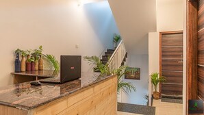 A modern kitchen with a laptop on the counter, a wooden cabinet, and a staircase leading to a landing with a door. - The Cloud Berry (Kasauli)
