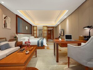 Een hotelkamer met een bed, een slaapbank, een bureau en een stoel.