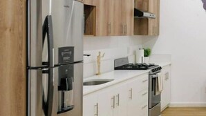 Een moderne keuken met houten kastjes, roestvrijstalen apparatuur en een wit aanrecht.
