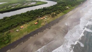 Luchtbeeld van een kustgebied met een rivier, een strand en verspreide huizen.