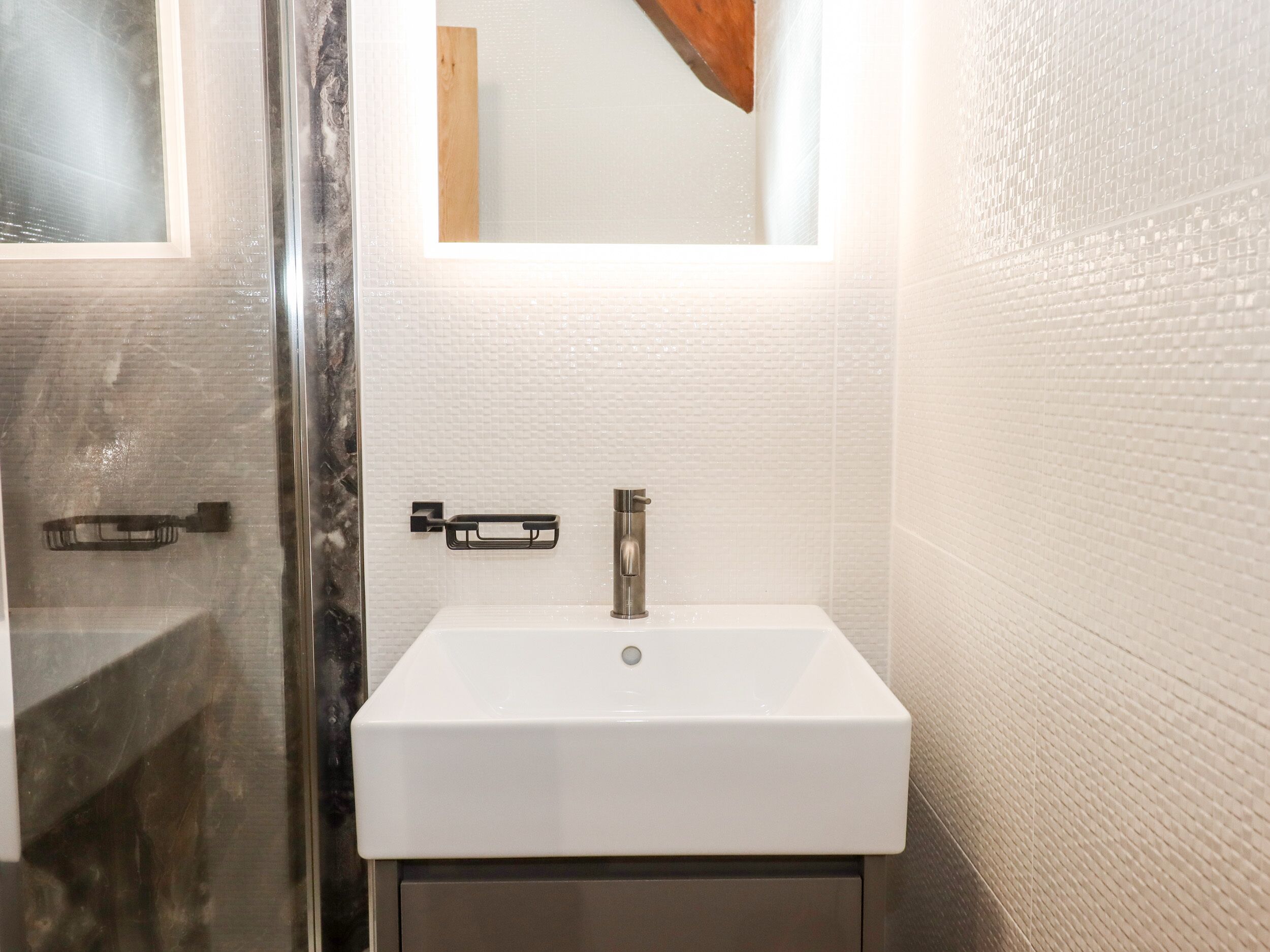 A bathroom with a white sink, a mirror, and a shower area.