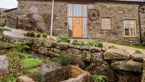 Un edificio de piedra con puerta de madera, ventana y chimenea.