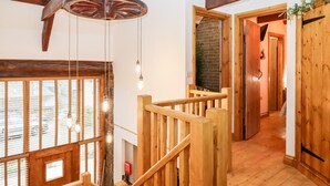 Una escalera de madera con diseño rústico, una lámpara colgante y vistas al exterior a través de amplios ventanales.